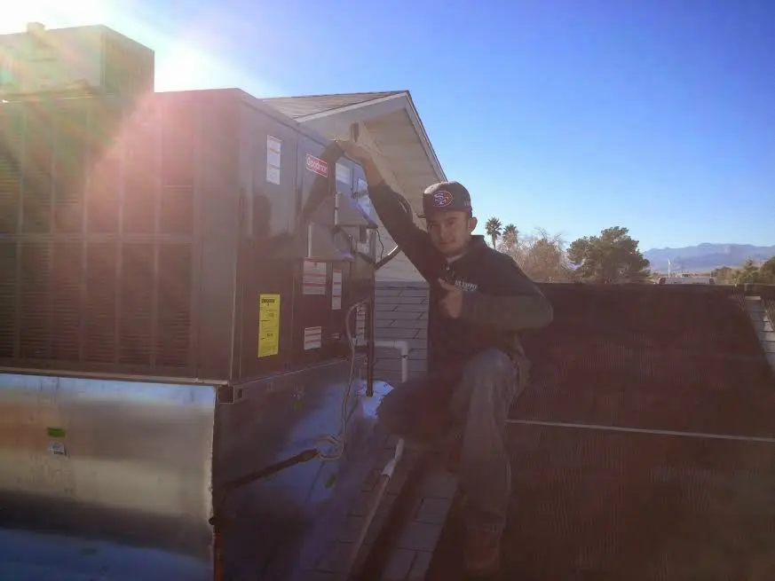 HVAC technician performing Air Duct Cleaning on a rooftop unit in Alpine